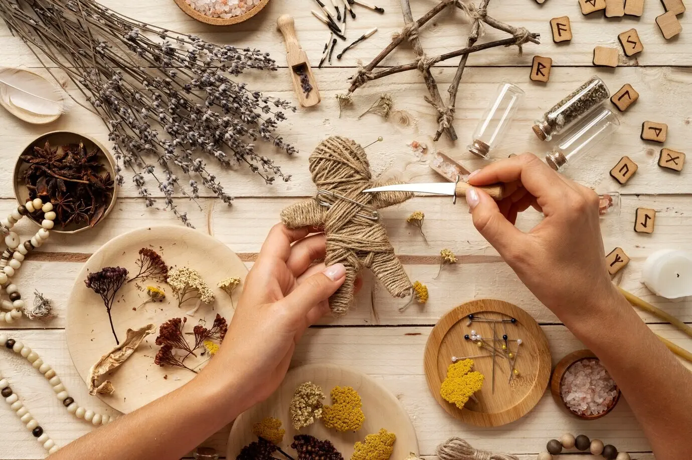 Draufsicht: Eine Hand sticht in eine Voodoo-Puppe.