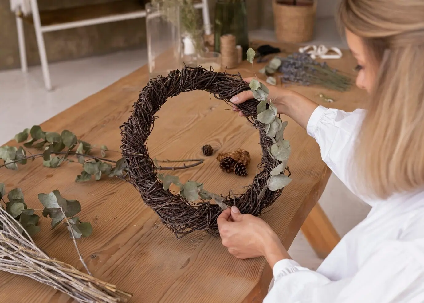 Frau, die ihr eigenes Arrangement aus getrockneten Blumen zusammenstellt.